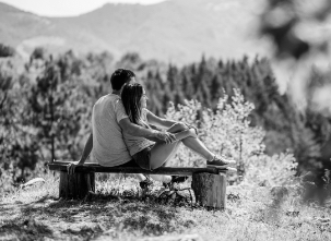 A couple sitting on a bench in a scenic outdoor setting