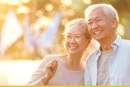 A happy elderly couple smiling together outdoors during sunset.