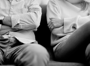 A close-up of a couple sitting apart on a couch