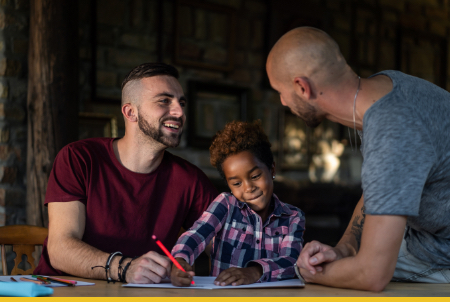 A joyful scene of a child drawing at a table with two adults