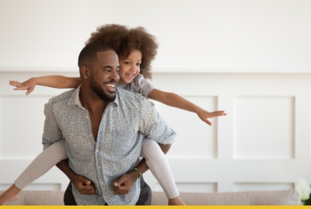 A joyful father carrying his daughter on his back