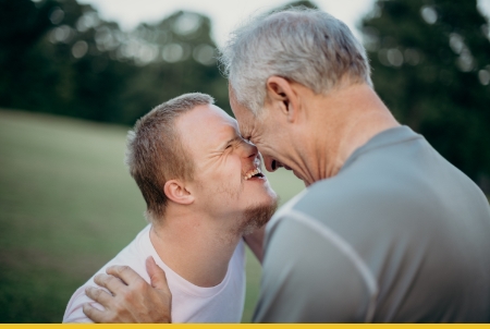 Two men smiling and sharing a joyful moment outdoors