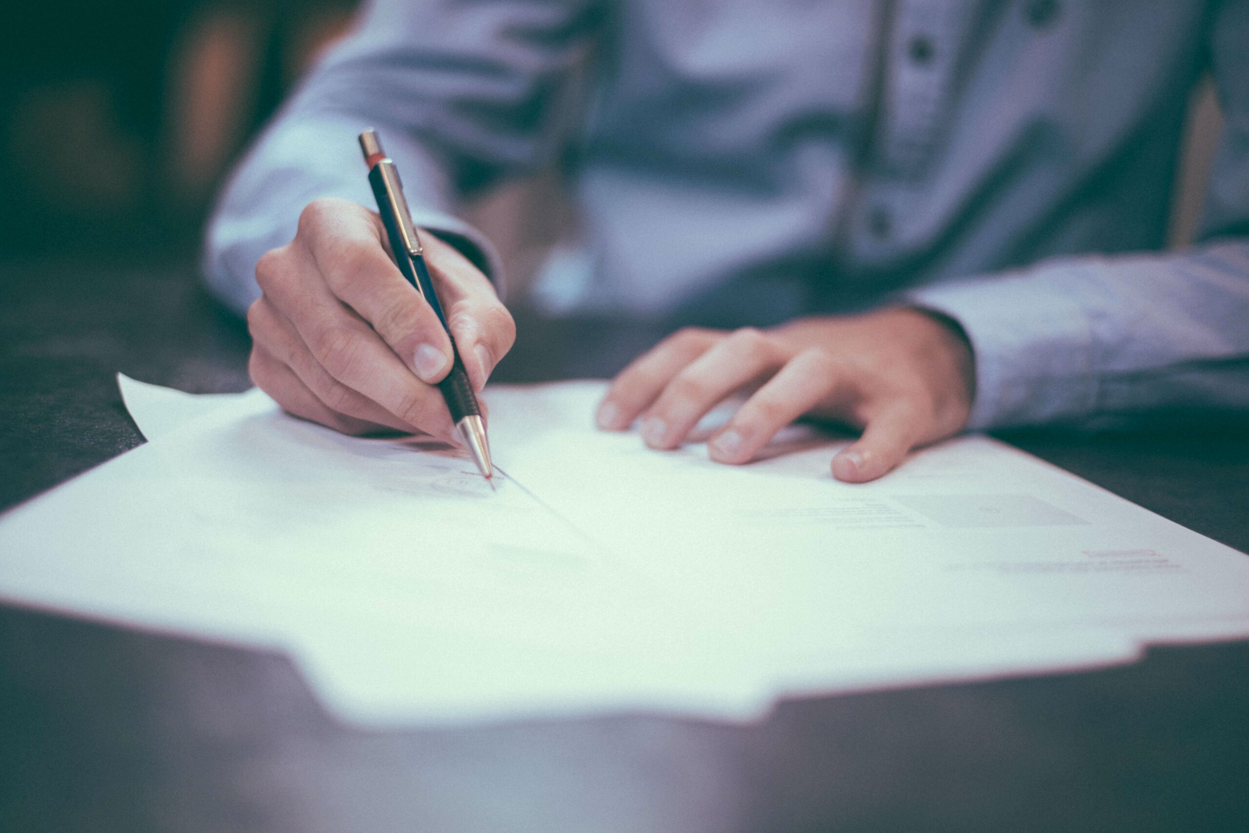 Man signing documents on a table|Secure Your Vision: 5 Estate Planning Tips for Seattle Entrepreneurs