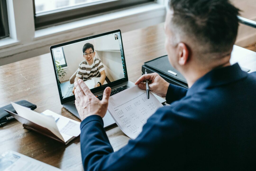 Two men on a video chat reviewing paperwork