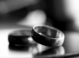 Close-up of two wedding rings on a reflective surface in black and white.