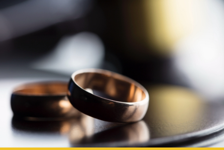 Close-up view of two wedding rings on a wooden surface with soft lighting